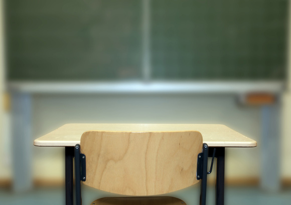 an image of an empty desk before a green chalkboard