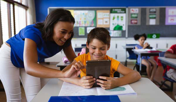 A special education teacher teaches her student on a tablet in the special education class.