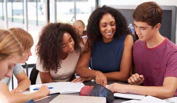 A special education teacher teaching a diverse group of middle school students in their classroom