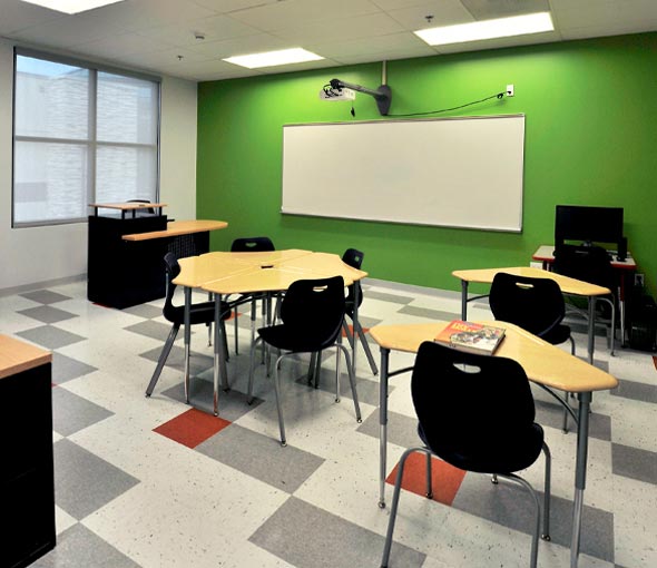 A classroom with green walls and empty desks at Green Tree School